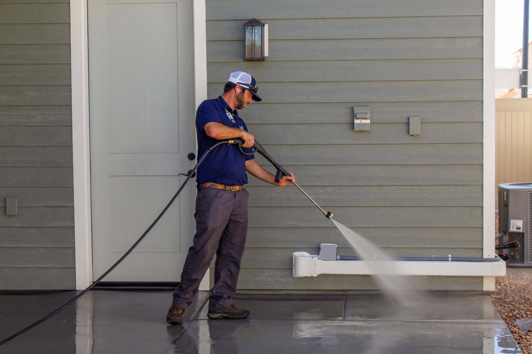Advanced Window Cleaning professional pressure washing concrete by gray house