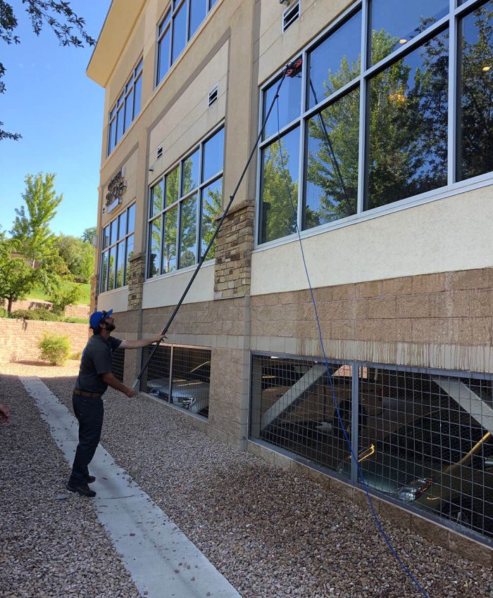 Advanced Window Cleaning professional in blue hat cleaning commercial property window